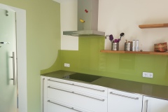 Grüne Glasrückwand hinter einer Küchenzeile