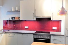 Rote Glas-Küchenrückwand mit Steckdosen